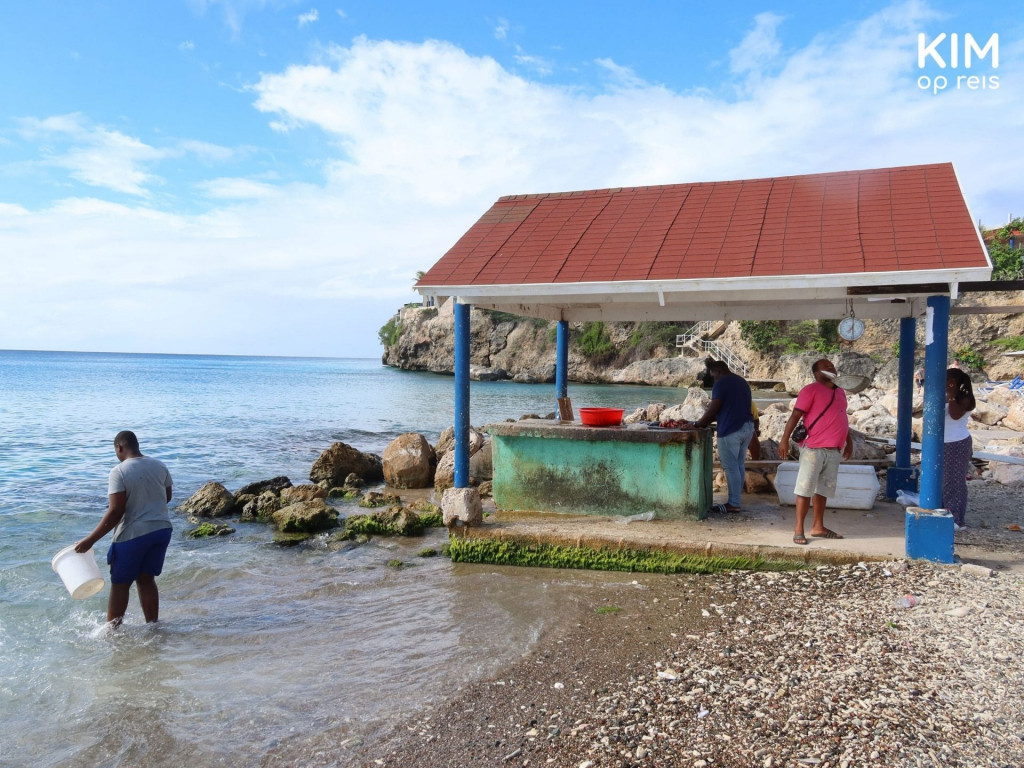 Playa Grandi vissers maken vis schoon: een overdekte vissershut met een werkplaat waar enkele vissers staan te werken